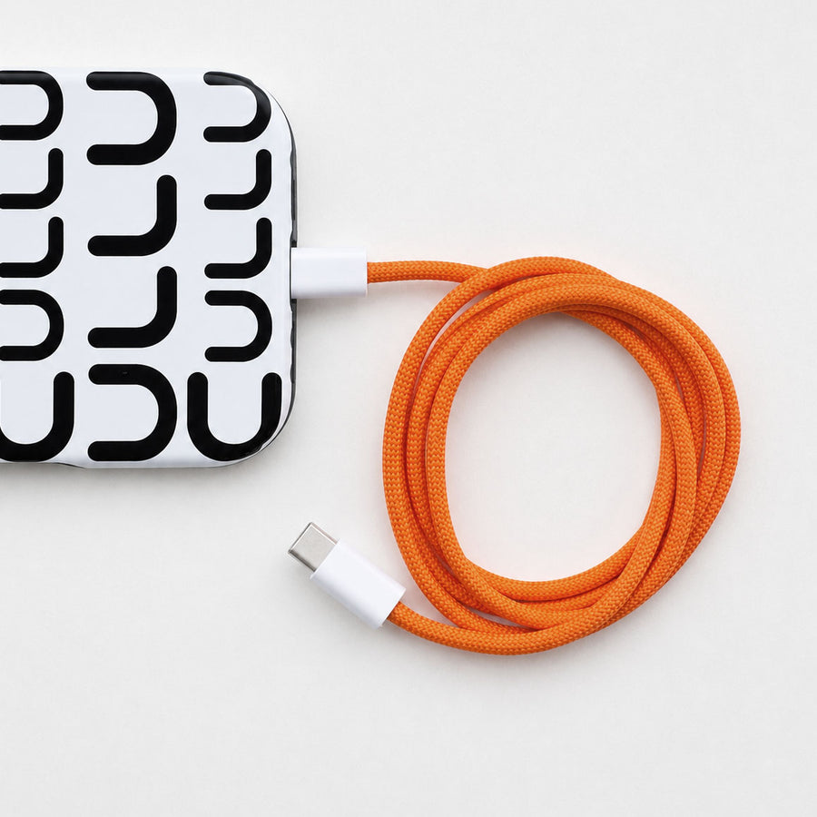 Oransje flettet USB-C-kabel koblet til iPhone 16 Pro Max