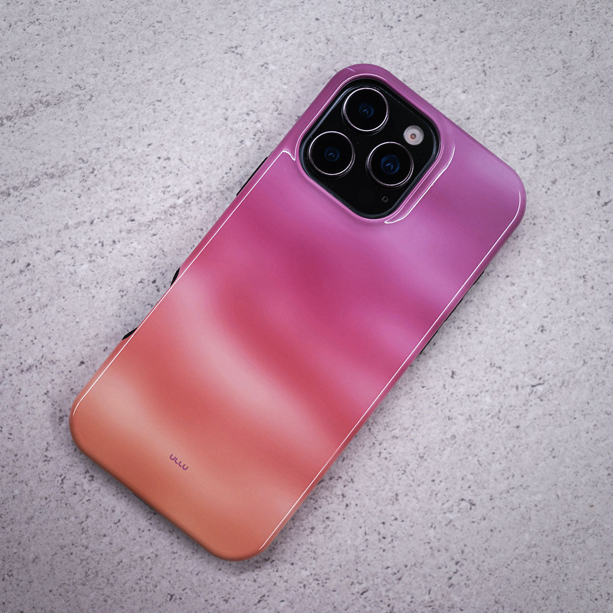 iPhone 16 Pro Max deksel Lilladis med en vakker lilla, rosa og oransje gradient på en lysegrå overflate.