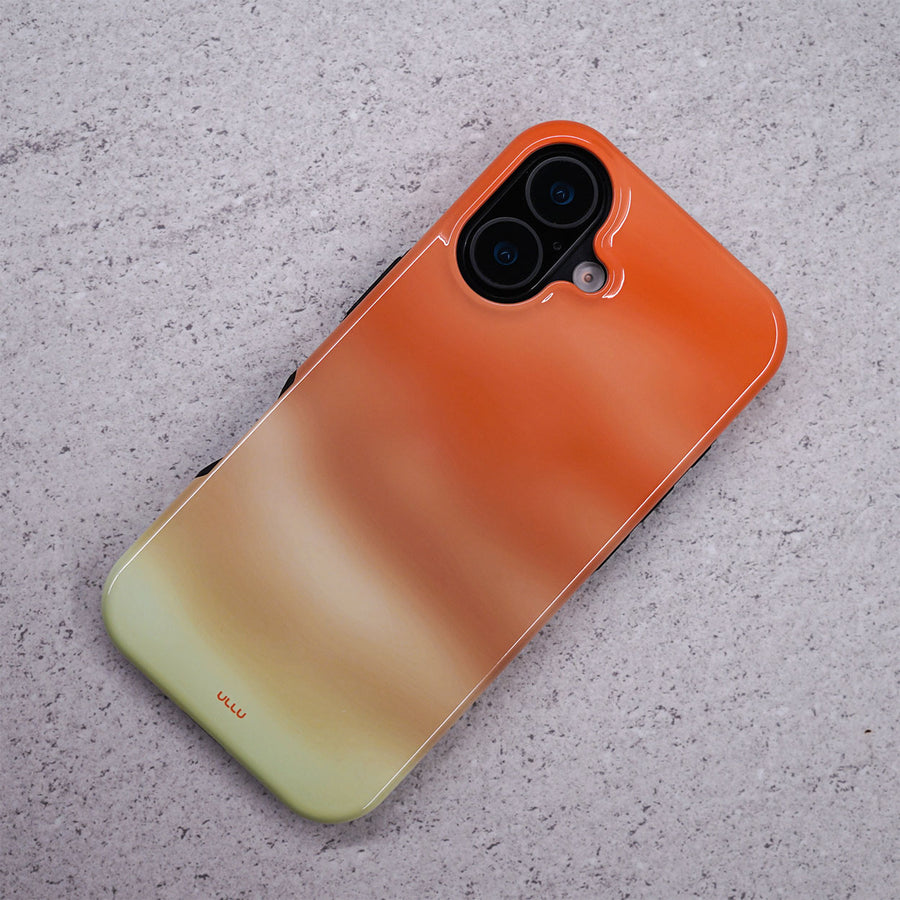 iPhone 16 deksel Koraldis med en varm korall, oransje og beige gradient på en lysegrå overflate.