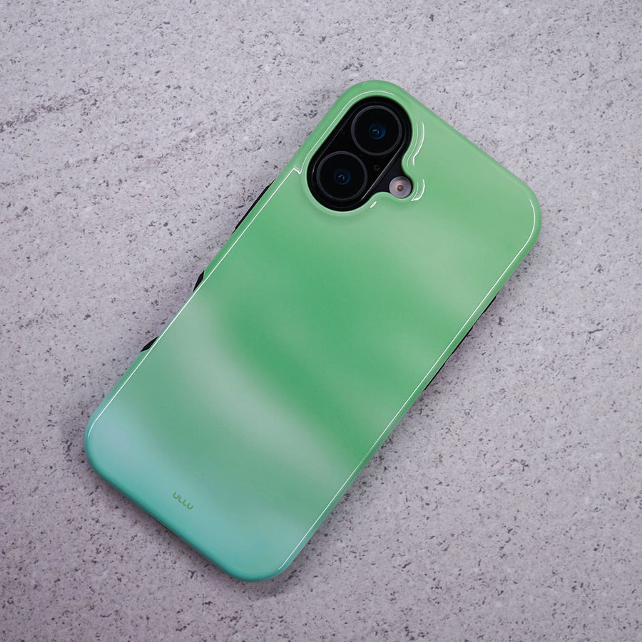 iPhone 16 deksel Myntdis med en myk myntgrønn og lys grønn gradient på en lysegrå overflate.